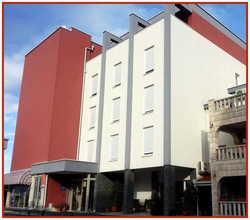 Hotel Dina في ميديوغوريه: مبنى كبير احمر وابيض بالقوس