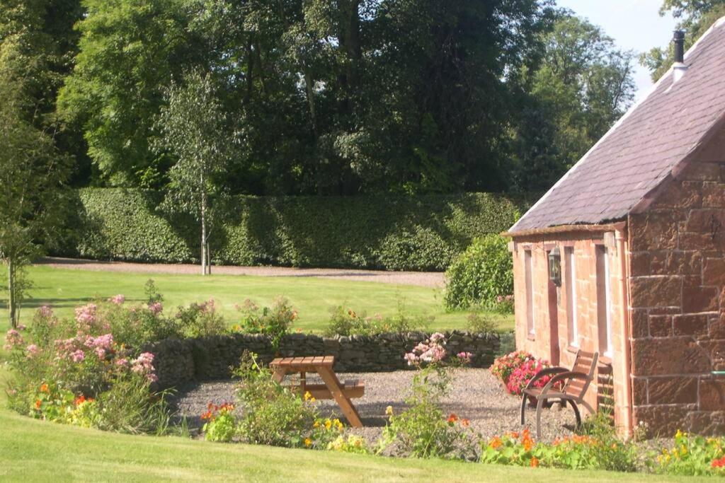 un jardín con un banco y un cobertizo en Harleyburn Cottages - Stables and Saddlery en Melrose