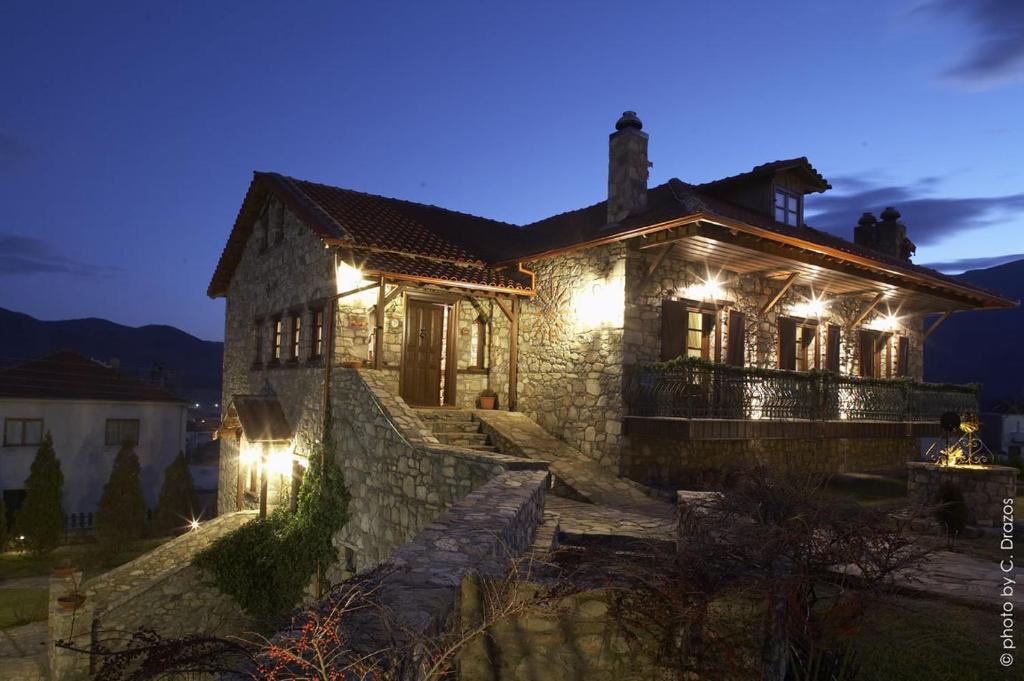 una casa de piedra con luces encendidas por la noche en Guesthouse Agonari, en Sklíthron