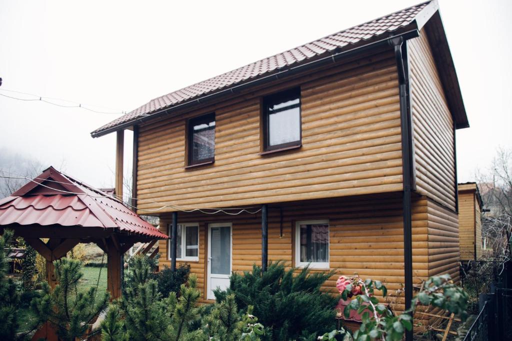 una casa in legno con un gazebo di fronte di Cottage Nezabudka a Jaremče