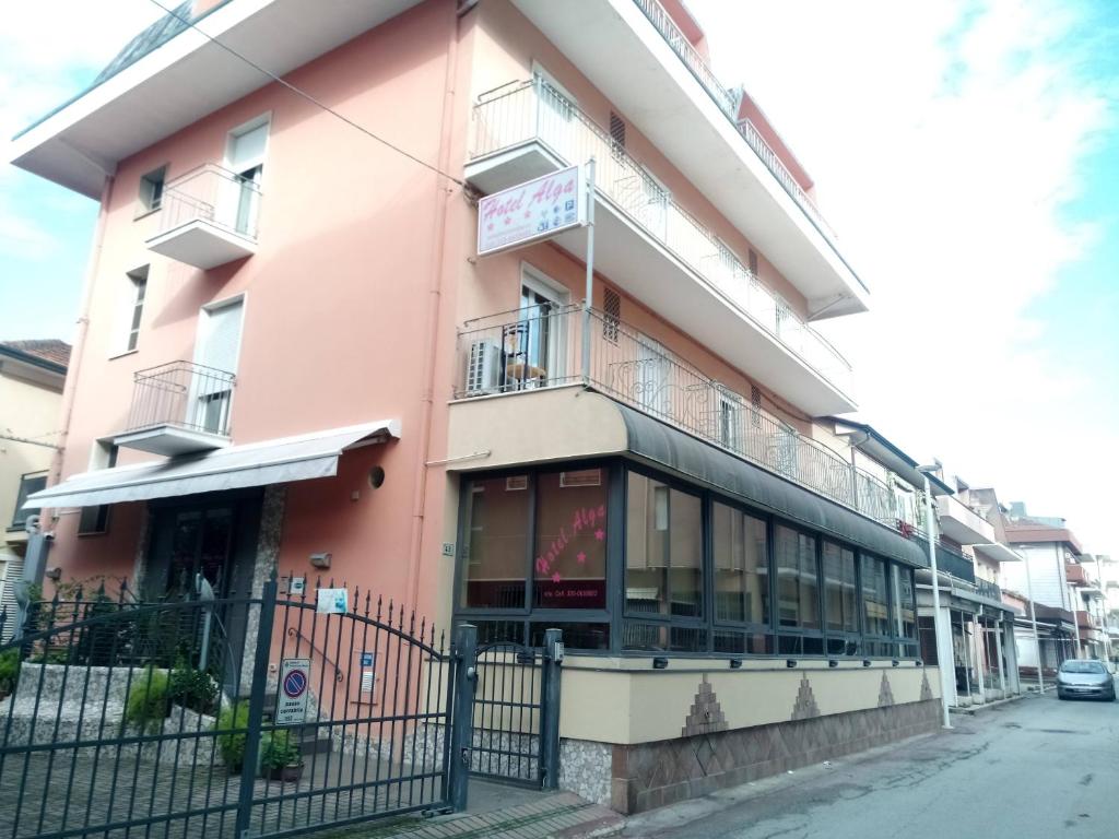 un edificio rosa con una valla delante en Hotel Alga, en Bellaria-Igea Marina