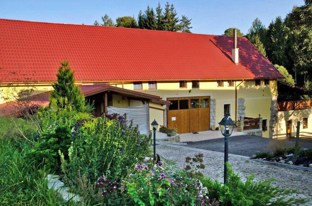 uma casa com um telhado vermelho e um jardim em Penzion Tuček Adršpach em Adrspach