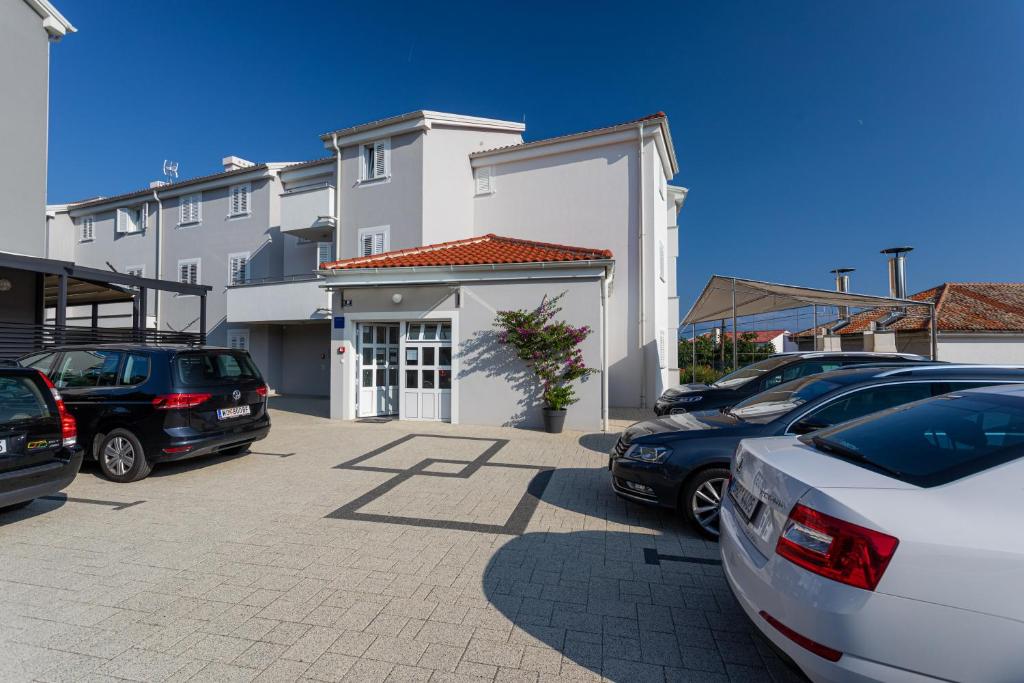 a parking lot with cars parked in front of a building at Apartments Crnekovic Tomislava 8 in Baška