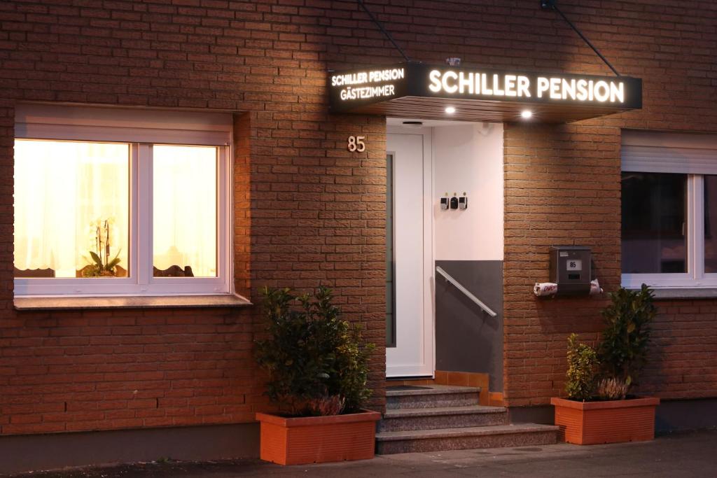 un bâtiment avec une porte blanche et un panneau sur celui-ci dans l'établissement Schiller Pension, à Bielefeld