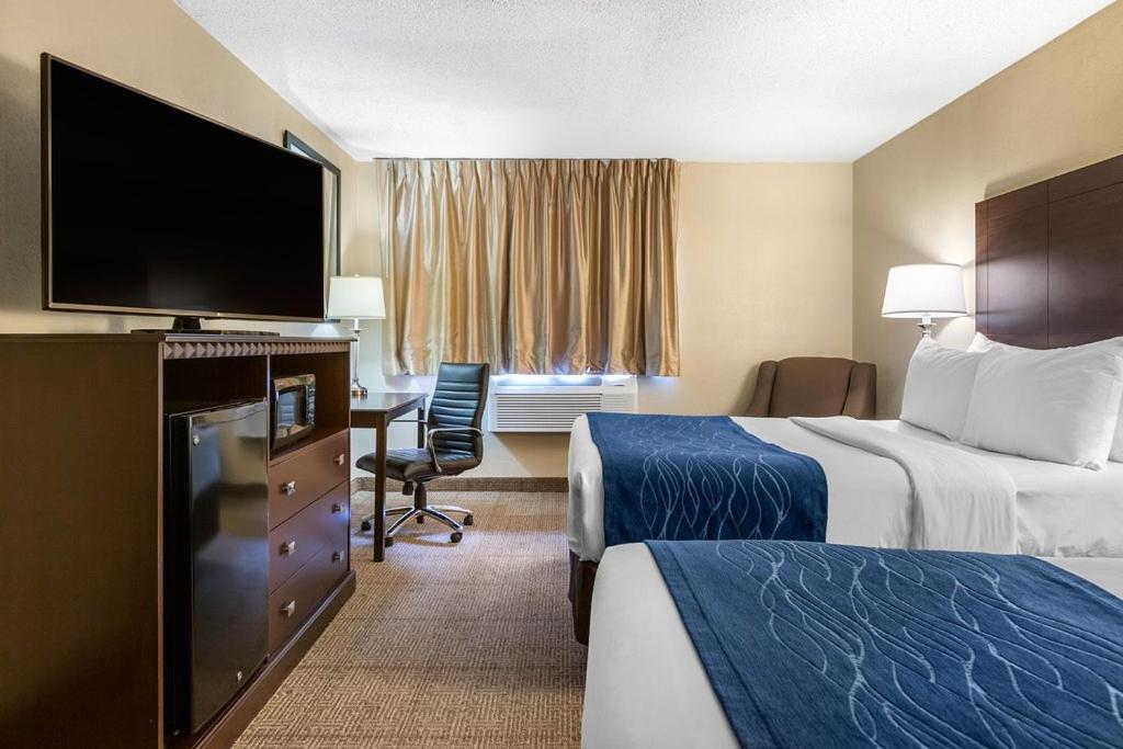 a hotel room with two beds and a flat screen tv at Comfort Inn Grand Rapids Airport in Grand Rapids