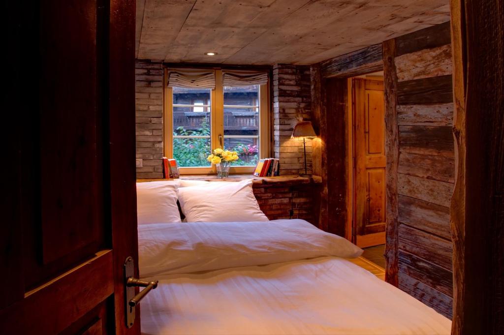 a bedroom with two beds in a room with a window at Luxury Chalets & Apartments by Mountain Exposure in Zermatt