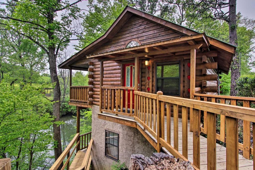 uma cabana de madeira na floresta com um deque em Riverfront Cabin with Fire Pit - 5 Mi to Pigeon Forge em Sevierville