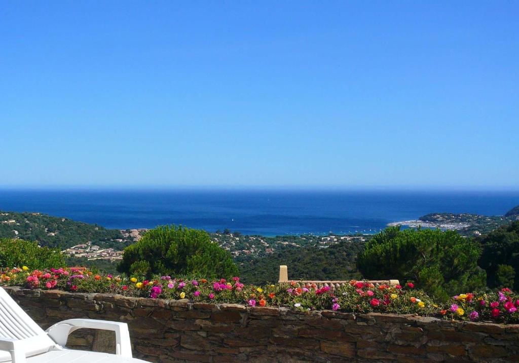 un mur en pierre avec deux chaises blanches et des fleurs dans l'établissement Villa Les Albizias, à Cavalaire-sur-Mer