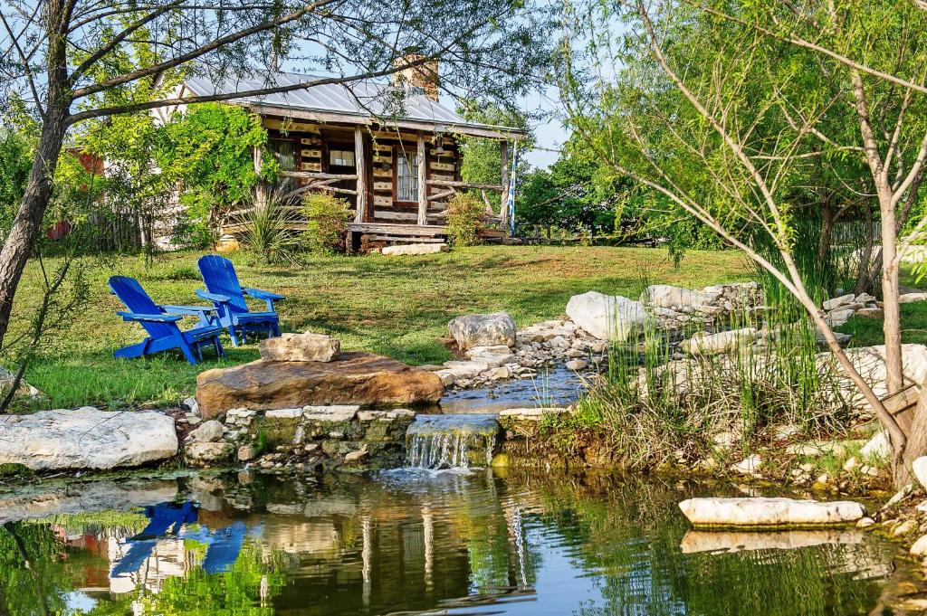 um quintal com um lago e duas cadeiras e uma casa em Barons CreekSide Resort em Fredericksburg