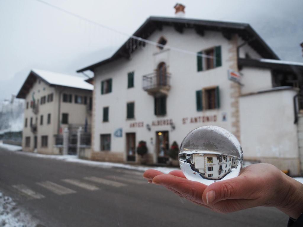una persona sosteniendo una bola de cristal delante de un edificio en Antico Albergo Sant'Antonio, en Fonzaso