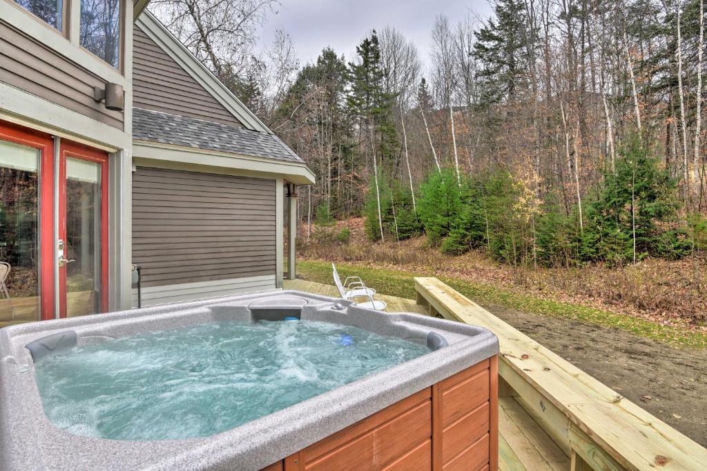 a hot tub on a deck in front of a house at Ski-in Condo with Hot Tub on Burke Mtn Slopes! in East Burke