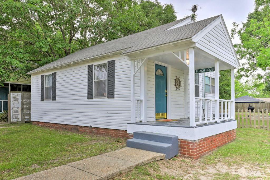 a small white house with a blue door at Gulfport Home with Deck and Grill, Walk to Beach! in Gulfport