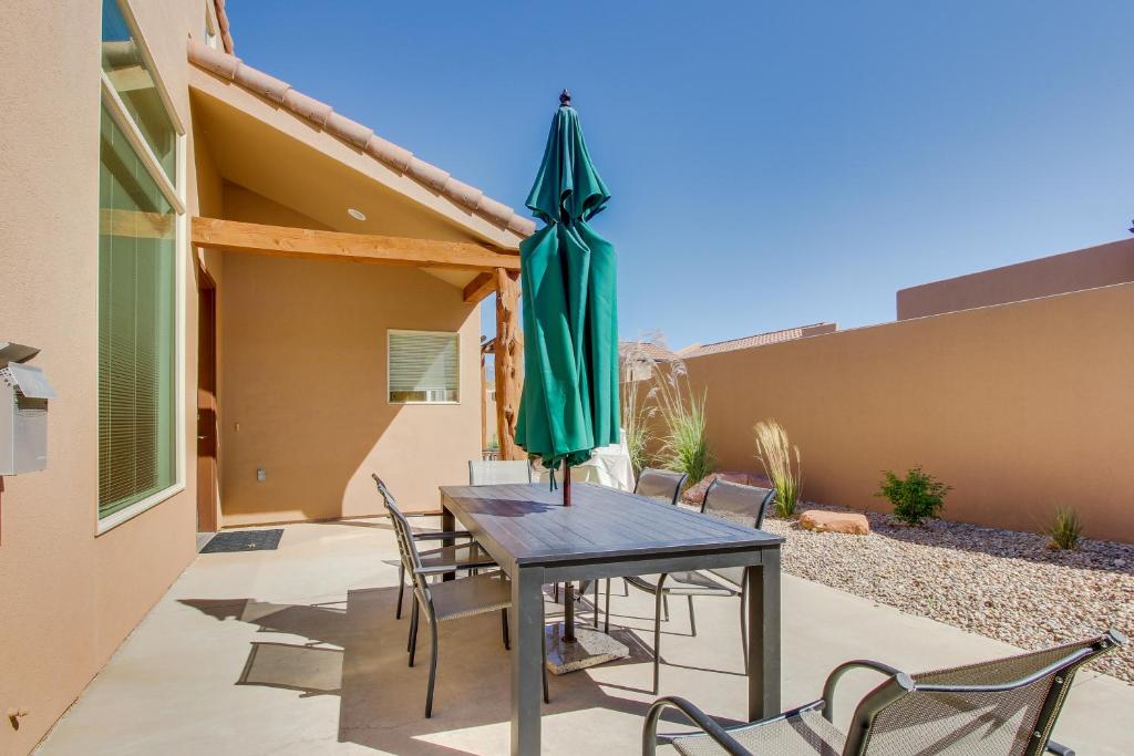 een patio met een tafel met een groene parasol bij Rim Village Two-Bedroom in Moab