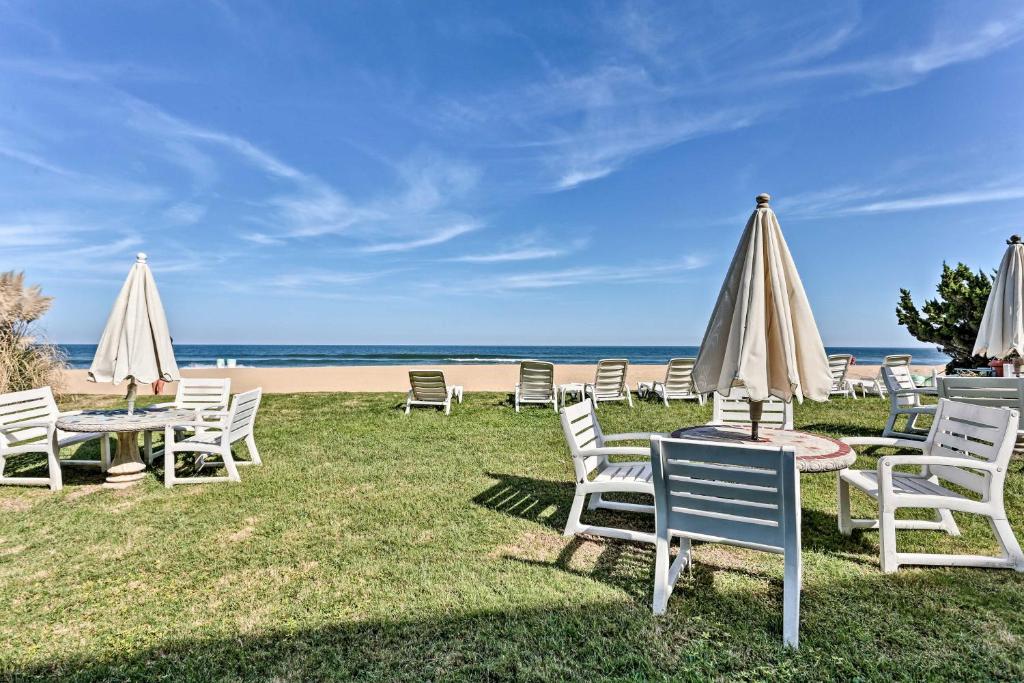 un grupo de sillas y sombrillas en la playa en Virginia Beach Studio with Balcony and Pool View!, en Virginia Beach