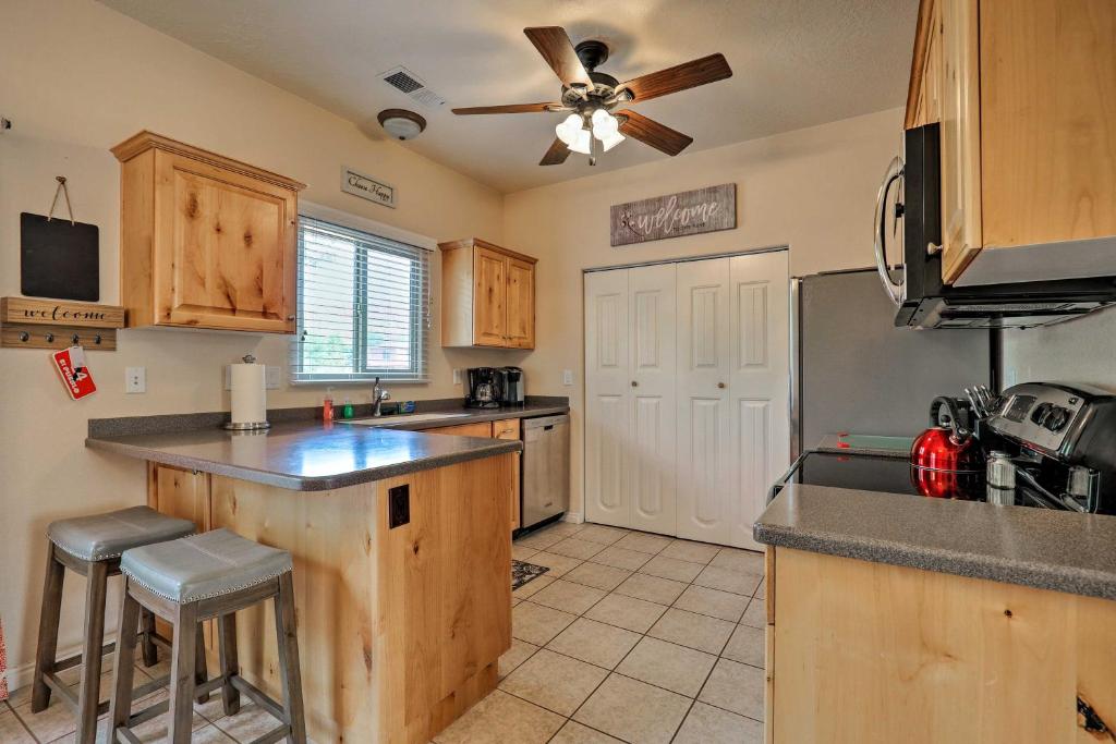 a kitchen with wooden cabinets and a ceiling fan at Kanab Condo with Pool and Patio, 30 Mi to Zion NP in Kanab