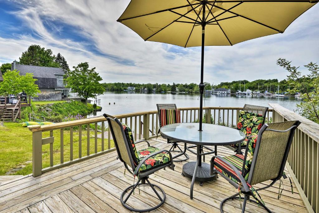 a table with chairs and an umbrella on a deck at Family Cottage on Chaumont Bay, Walk to Downtown in Chaumont