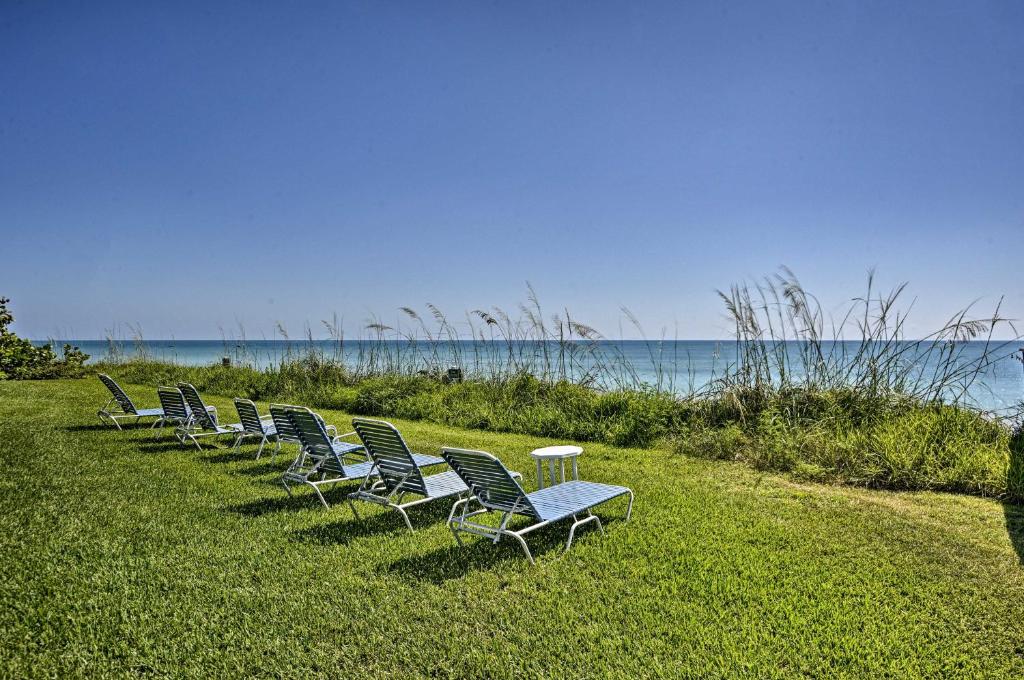 una fila di sedie sedute nell'erba vicino all'acqua di Oceanfront Vero Beach Condo with Balcony Views! a Vero Beach