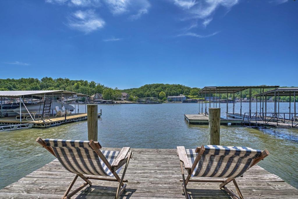two chairs sitting on a dock near the water at Lake of the Ozarks Home with Game Room, BBQ and Dock! in Osage Beach