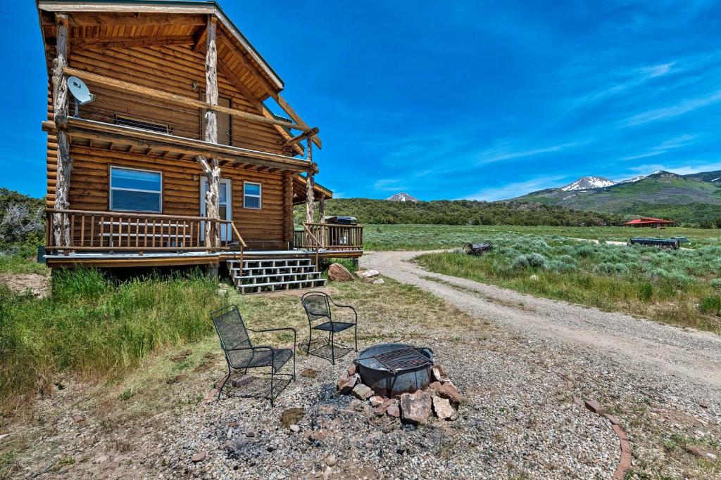 um chalé de madeira com 2 cadeiras e uma fogueira em Cabin with Fire Pit, Views and BBQ 18 Mi to Moab! em Moab