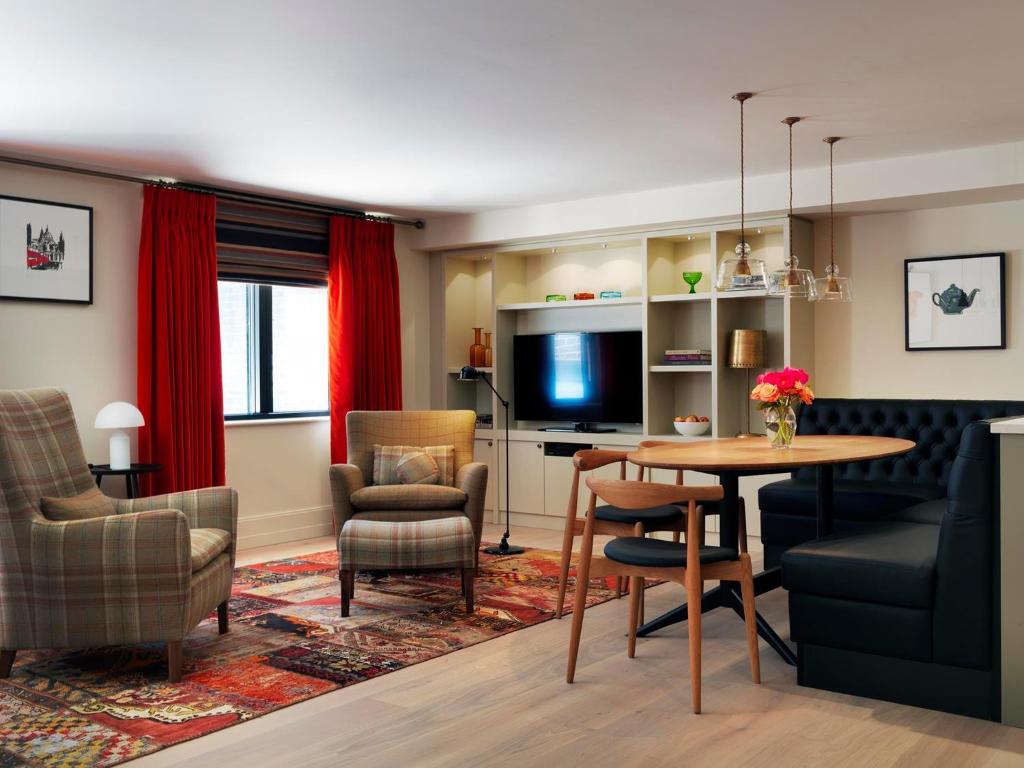 a living room with a table and chairs and a television at Cheval Knightsbridge in London