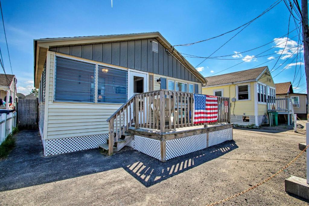Una casa con un porche con una bandera americana. en Hampton Cottage - Walk to Beaches and Marina!, en Hampton