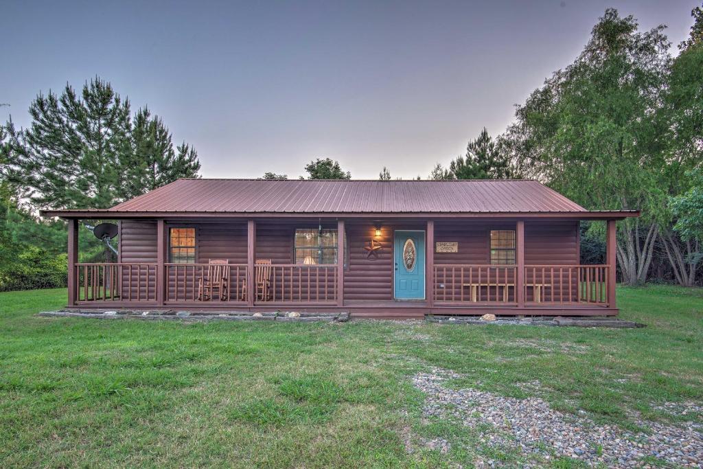 uma cabana de madeira com um alpendre e uma porta azul em Broken Bow Starlight Cabin with Private Hot Tub! em Broken Bow