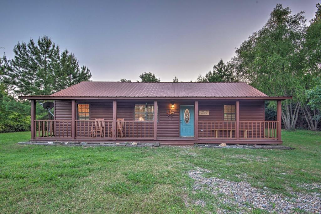 a log cabin with a porch and a blue door at Broken Bow Starlight Cabin with Private Hot Tub! in Broken Bow