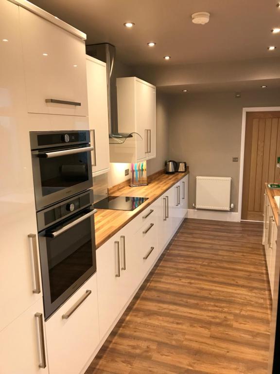 uma cozinha com armários brancos e electrodomésticos pretos em Cosy Vibes Central Cardiff House em Cardiff