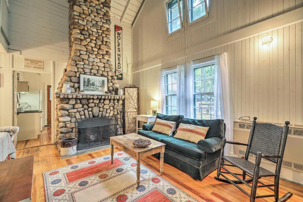 a living room with a couch and a stone fireplace at Saranac Lake Cabin with Beach Access in Lake Clear