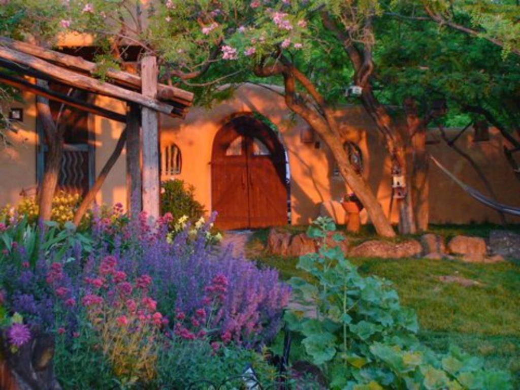 un dipinto di un giardino con fiori di fronte a una casa di Old Taos Guesthouse B&B a Taos