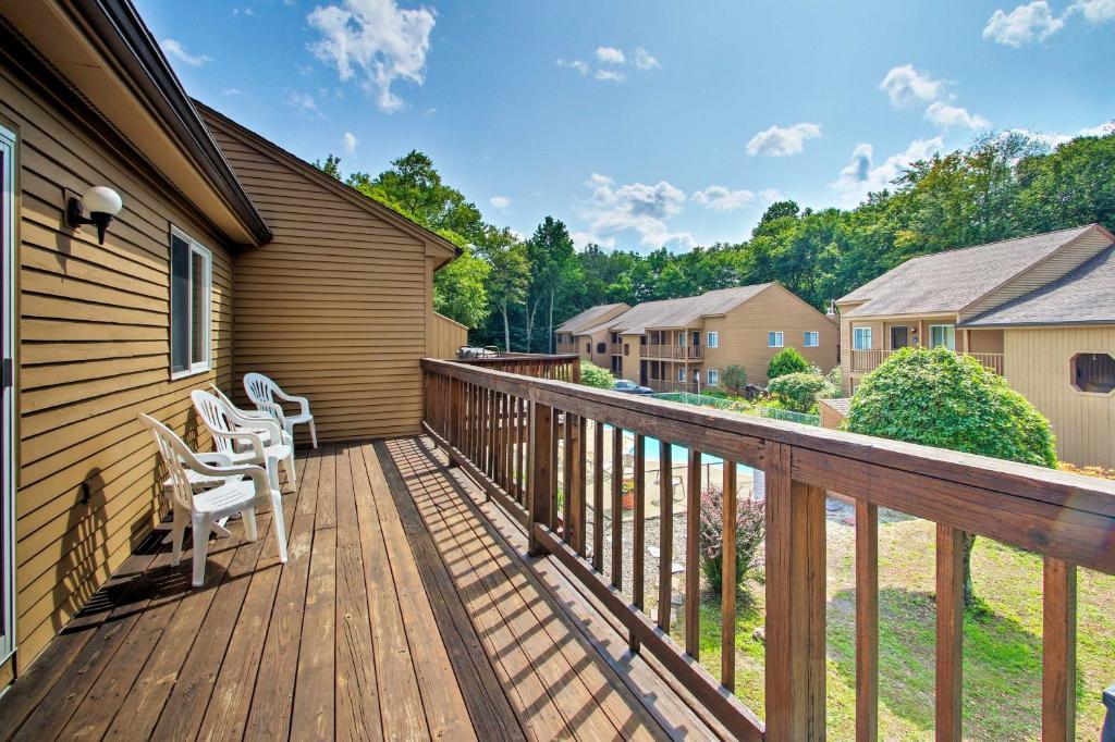 a wooden deck with white chairs on a house at Lincoln Condo with Pool Access - 6 Mi to Loon Mtn! in Lincoln