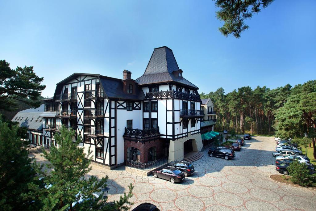 a large house with cars parked in a parking lot at Hotel Royal Baltic 4* Luxury Boutique in Ustka