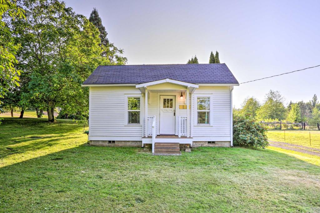 una pequeña casa blanca en un campo de hierba en Ferndale Cottage on Private 20 Acre Farm!, en Ferndale