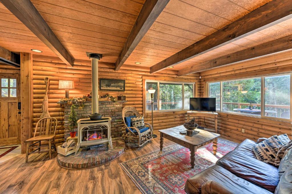 a living room with a fireplace in a log cabin at Amber Cabin with Hot Tub, Near Top Vineyards! in Pollock Pines