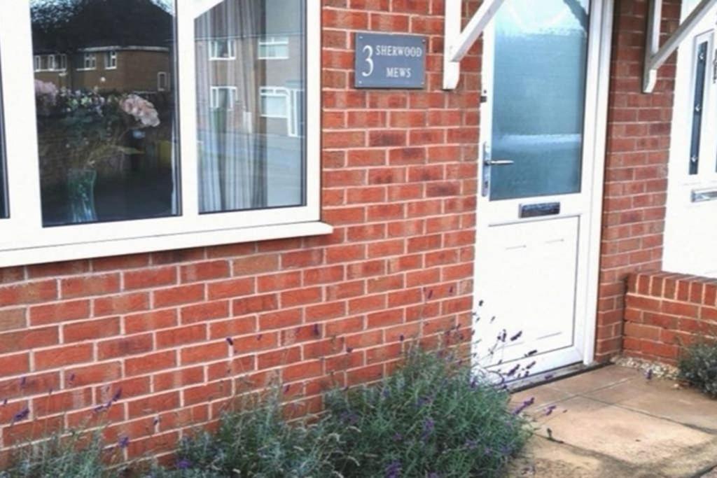 a brick house with a white door and a sign on it at Lavender House in Edwinstowe