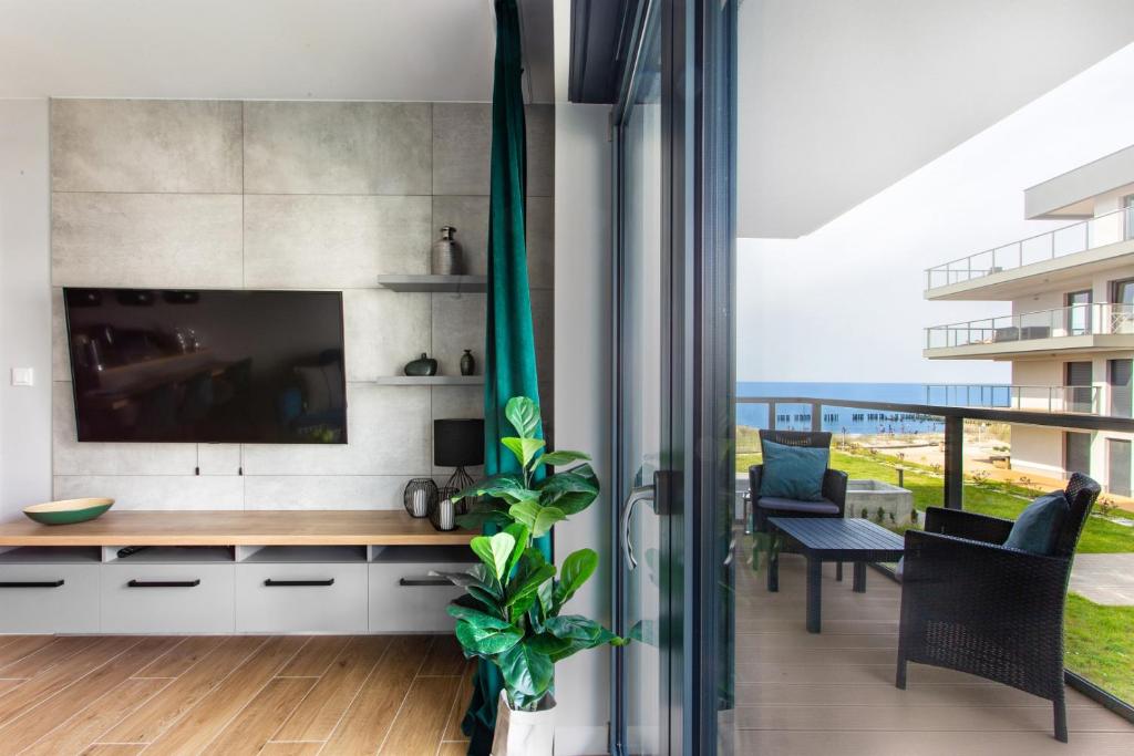 un soggiorno con TV e tavolo con una pianta di Apartament Gardenia Sea&Sun DZIWNÓW PRZY PLAŻY a Dziwnów
