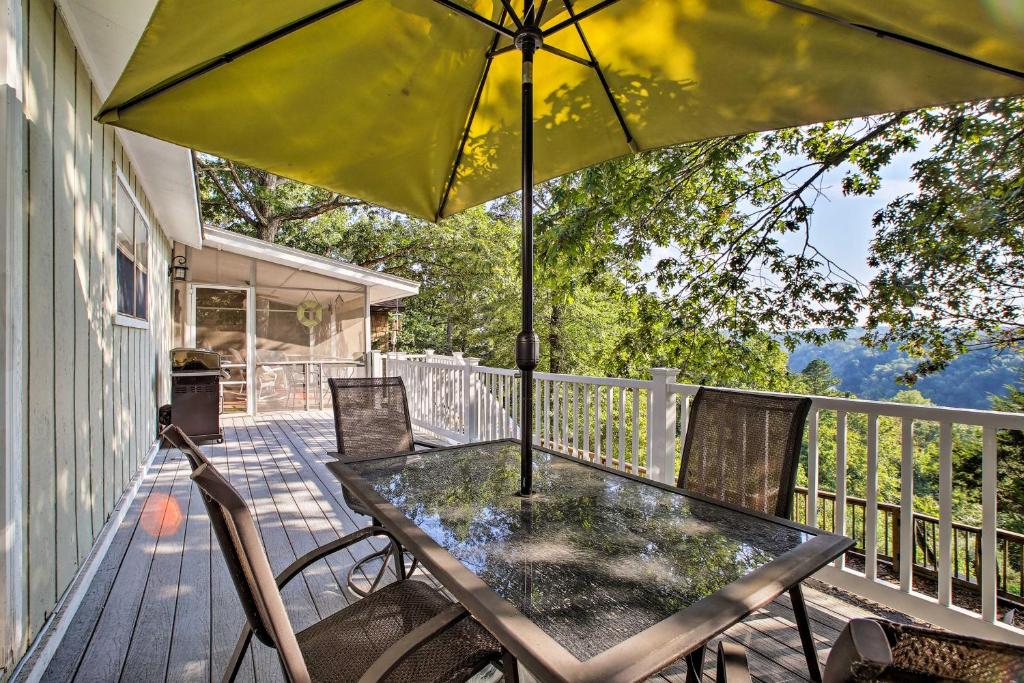 une table et des chaises sur une terrasse avec un parasol dans l'établissement Hillside Rogers Cottage with Beaver Lake Views!, à Rogers