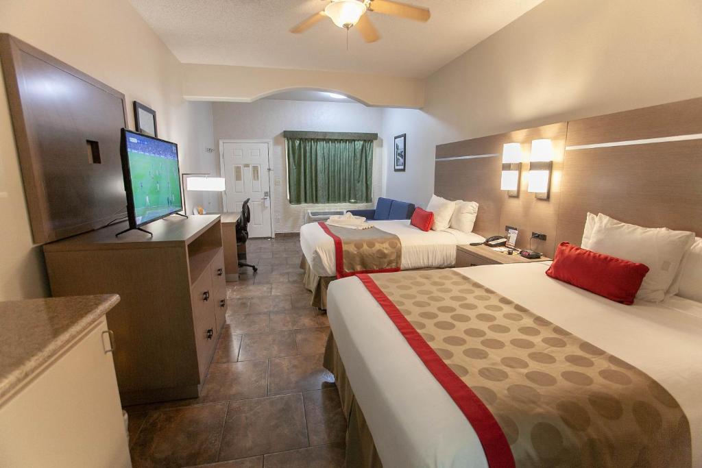 a hotel room with two beds and a flat screen tv at Ramada by Wyndham & Suites South Padre Island in South Padre Island