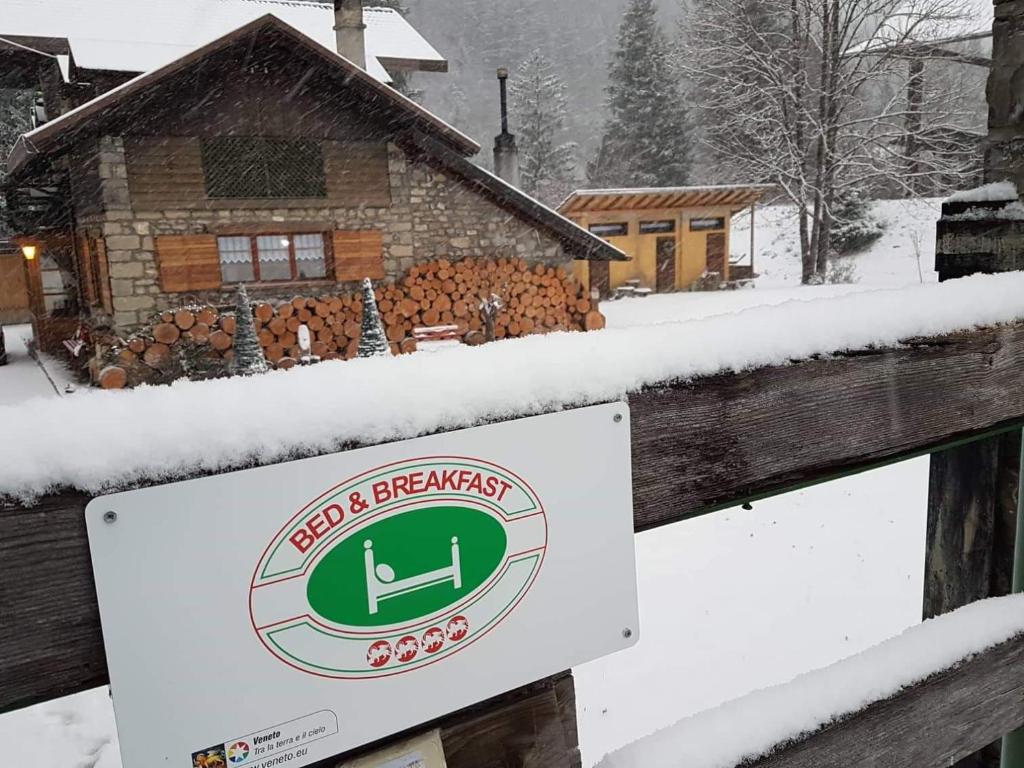 um sinal em frente a uma casa na neve em B&B ABETE BIANCO em Auronzo di Cadore