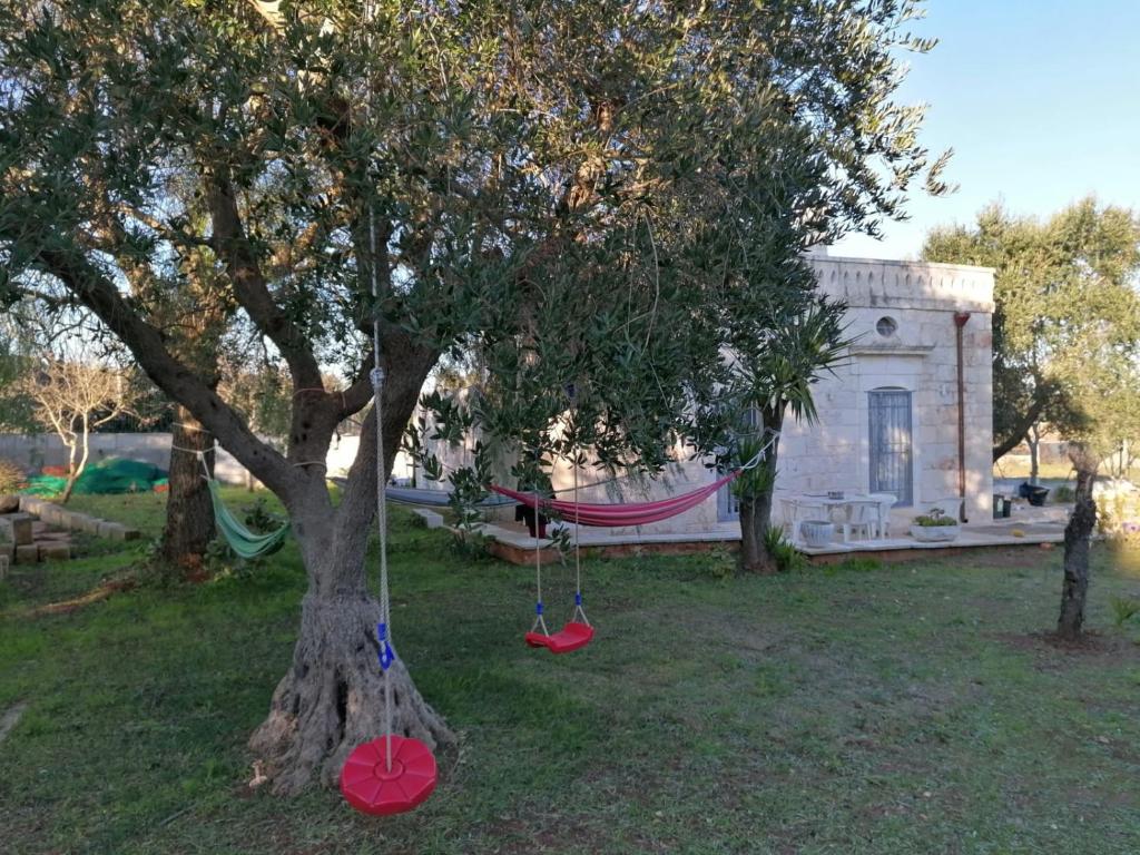 a tree with a hammock in front of a building at Il Casolare nel relax in Ostuni