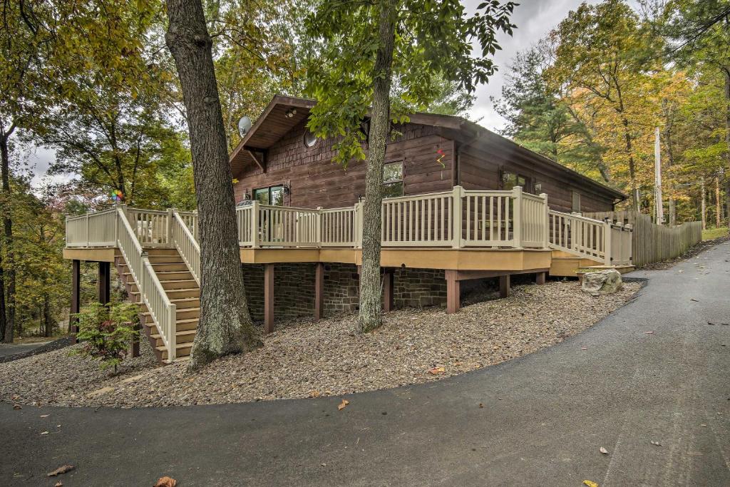 Cabaña de madera con terraza y escaleras en el bosque en Pet-Friendly Raystown Lakefront Cabin with BBQ Grill en Hesston