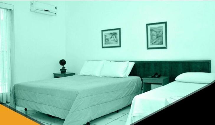um quarto com 2 camas e uma parede azul em Hotel Dourado em Alfenas