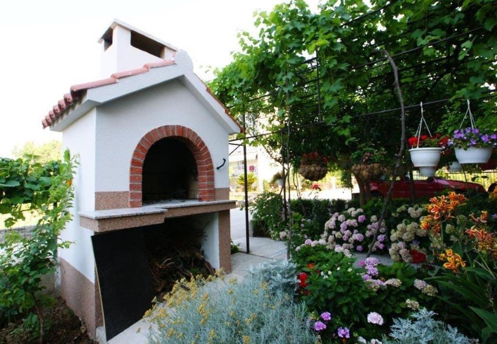 ein Vogelhaus in einem Garten mit Blumen in der Unterkunft Apts Milica - parking and garden in Kaštela