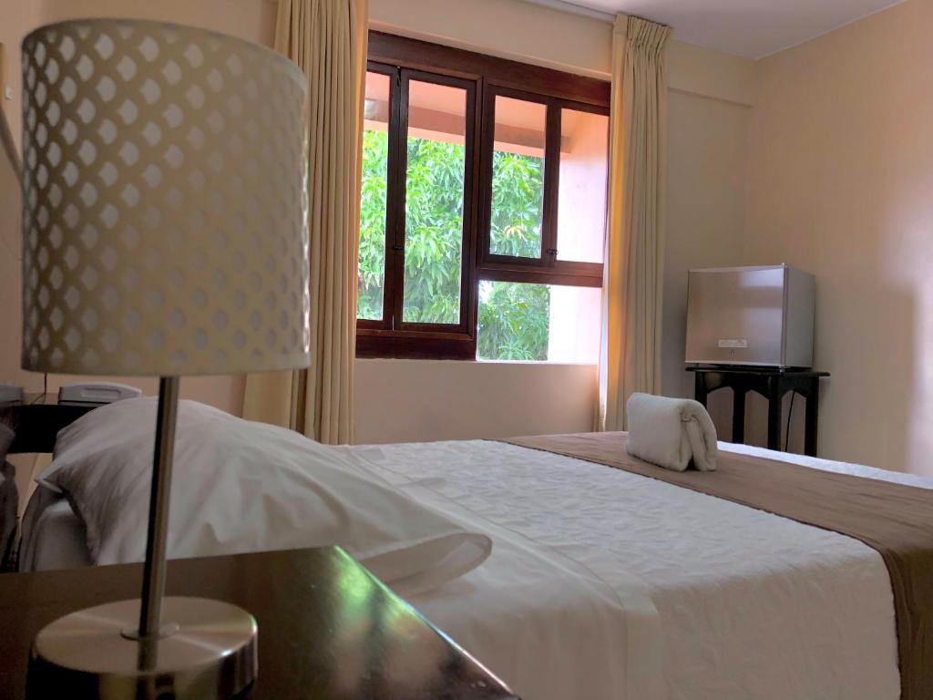 1 dormitorio con 1 cama con lámpara y ventana en Hotel Monte Azul, en Tarapoto