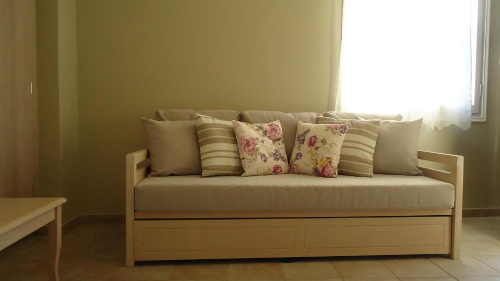 a couch with pillows on it in front of a window at House of Garden in Dhráganon
