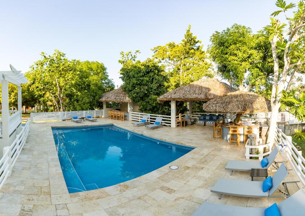 una piscina del complejo con sillas, mesas y sombrillas en Blue Paloma Bed & Breakfast, en Lucea