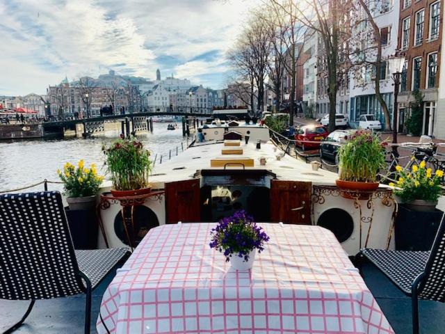 a boat on a river with a table and flowers on it at Romantic Houseboat in Amsterdam