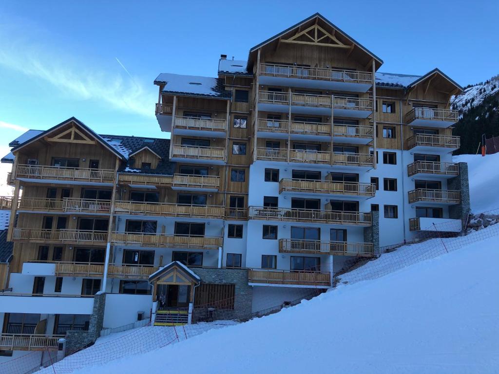 un grand immeuble situé au sommet d'une piste enneigée dans l'établissement *NEW* Bellevue D’Oz Ski In Ski Out Luxury Apartment (8-10 Guests), à Oz