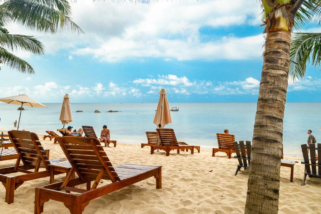 pessoas sentadas na praia com cadeiras e guarda-sóis em Vida Loca Sunset Beach Resort em Phu Quoc