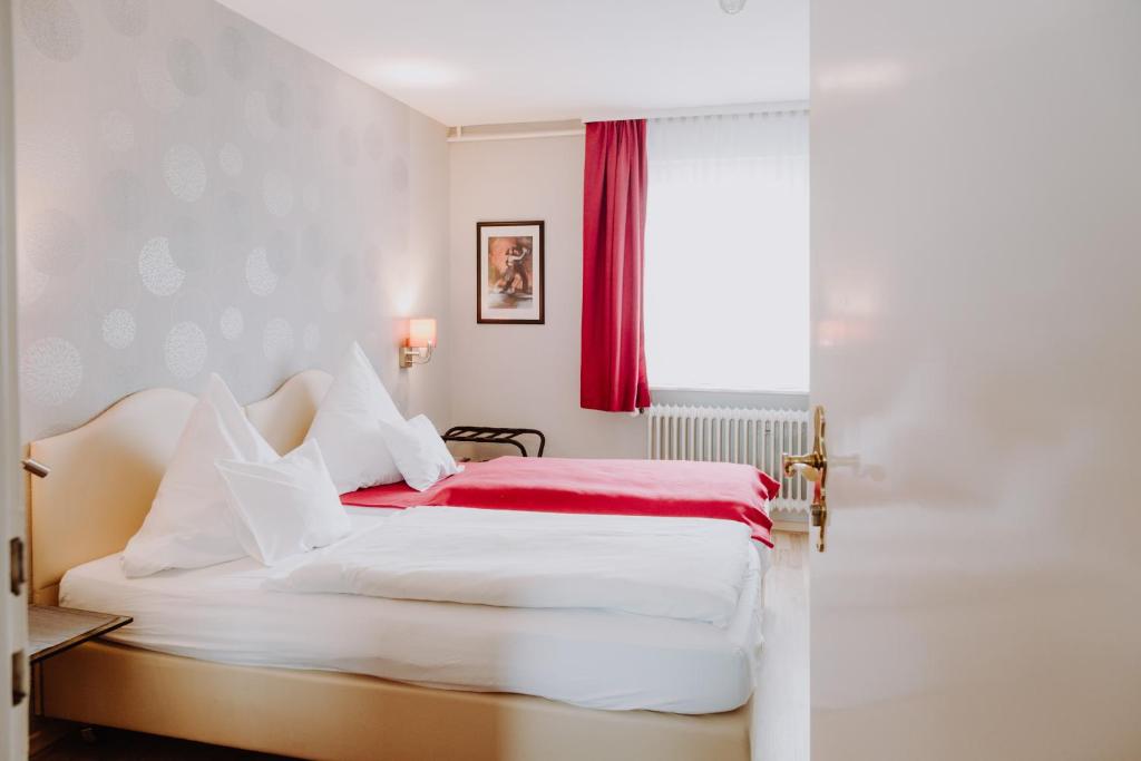 1 dormitorio con cama blanca y manta roja en Hotel Moorbadstuben, en Bad Buchau